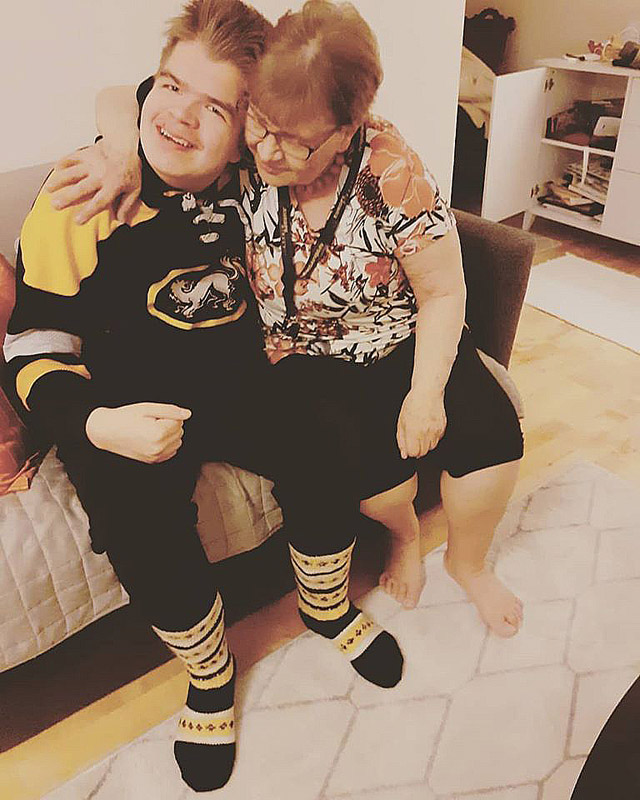 Uuno ja mummo halaavat. Uunolla on jalassaan mummon kutomat villasukat, joissa on Kärpät-joukkueen värit.